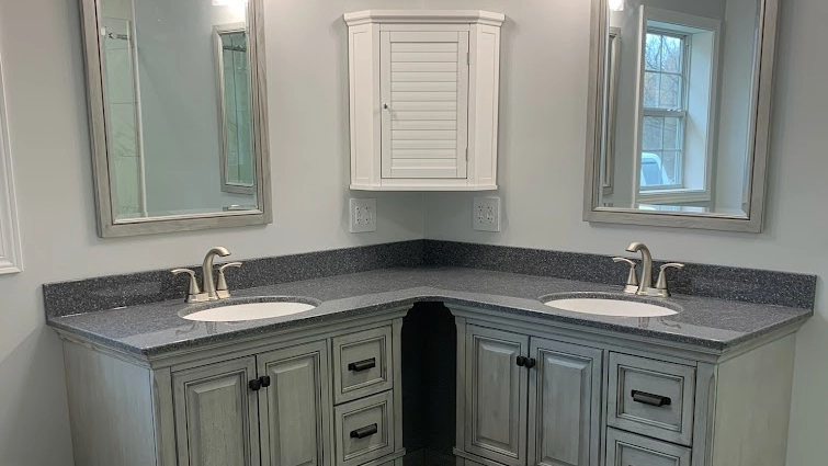 Modern onyx lavatory with dual sinks and granite countertop, featuring gray wooden cabinets and white wall-mounted medicine cabinet in a well-lit bathroom