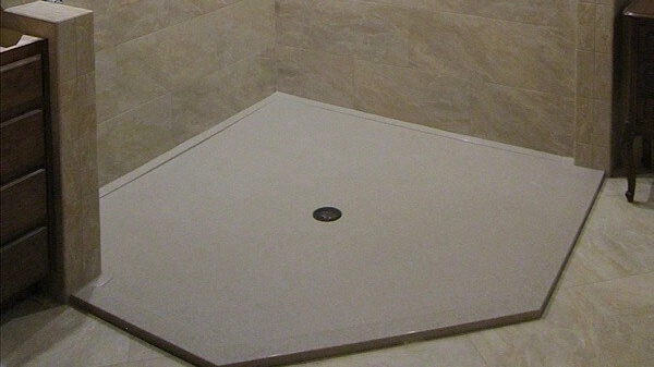 Neo-angle Onyx shower pan in a light color, featuring a flush central drain and subtle texturing for slip resistance.