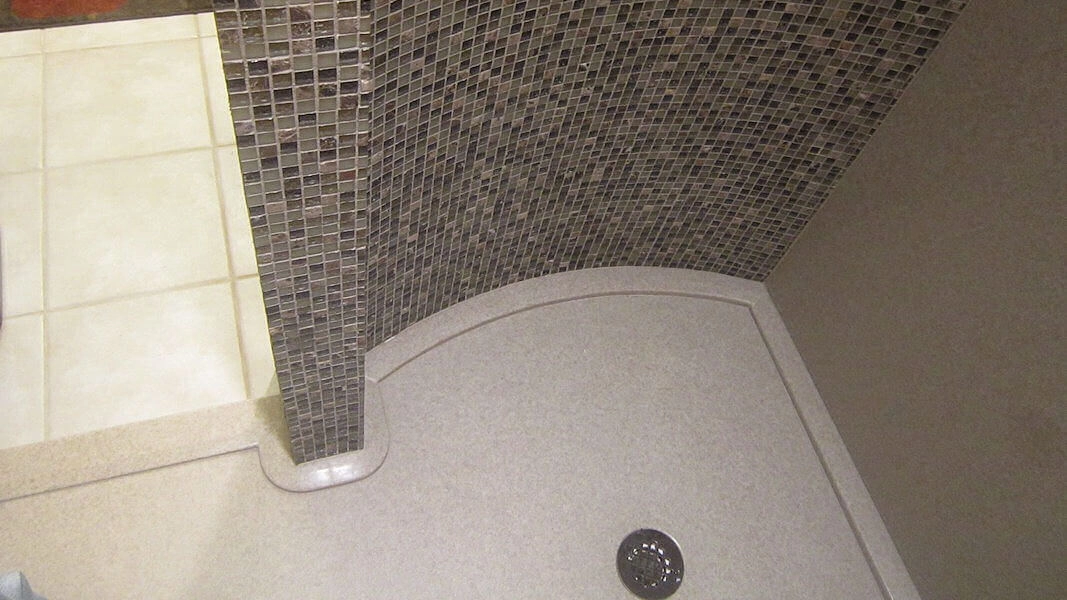 Curved Onyx shower base with a textured surface for safety and a round central drain.